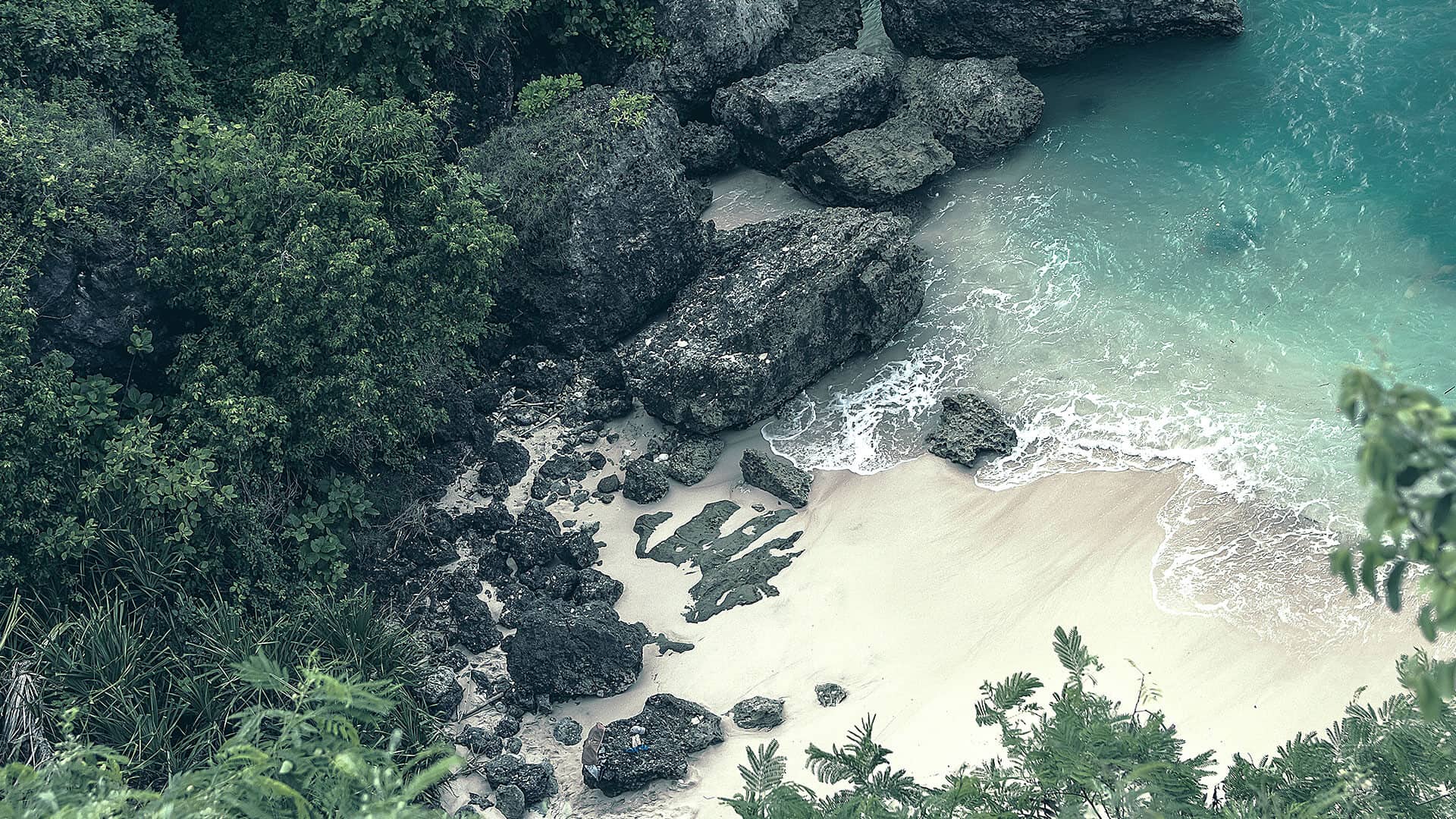 Tropical beach with turquoise water framed by a green headland