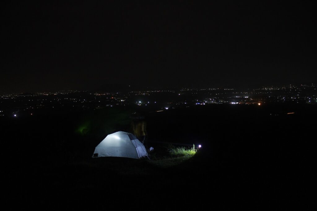 Packed camping gear beside a tent, sleeping bag, daypack and a head torch on the grass