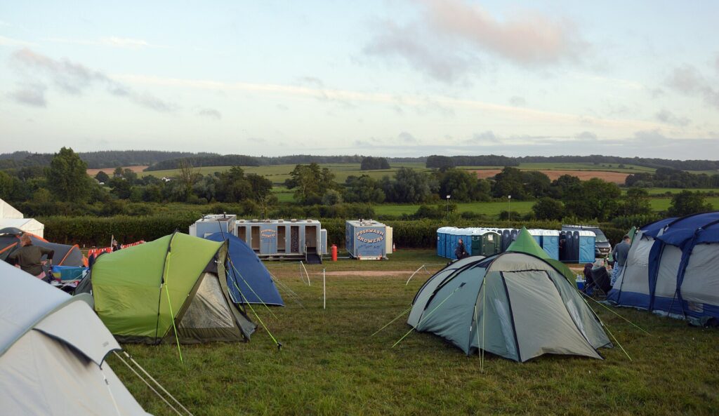 Row of tents on a festival campsite field in afternoon light