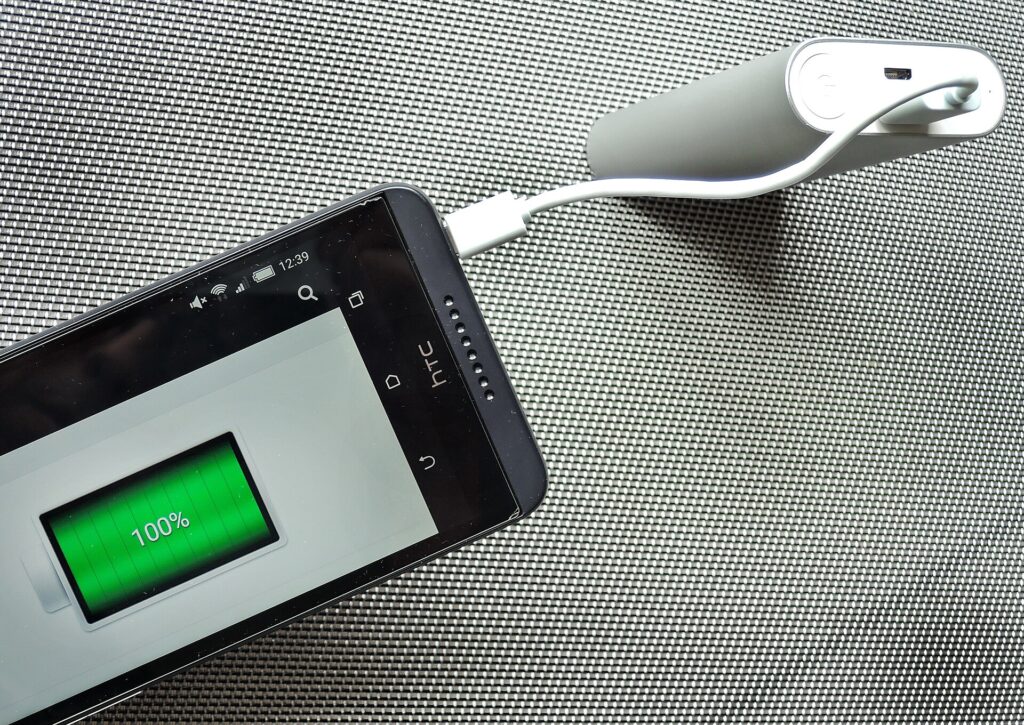 Power bank and coiled charging cable on a picnic blanket beside a tent