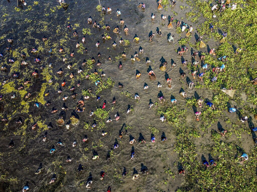 Festival-goer in layered clothing and gumboots standing on a muddy festival path