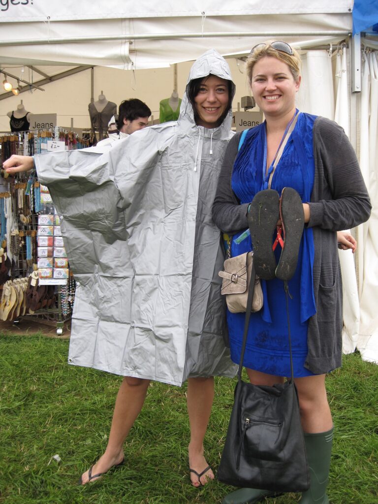 Festival-goers in rain ponchos at an outdoor festival