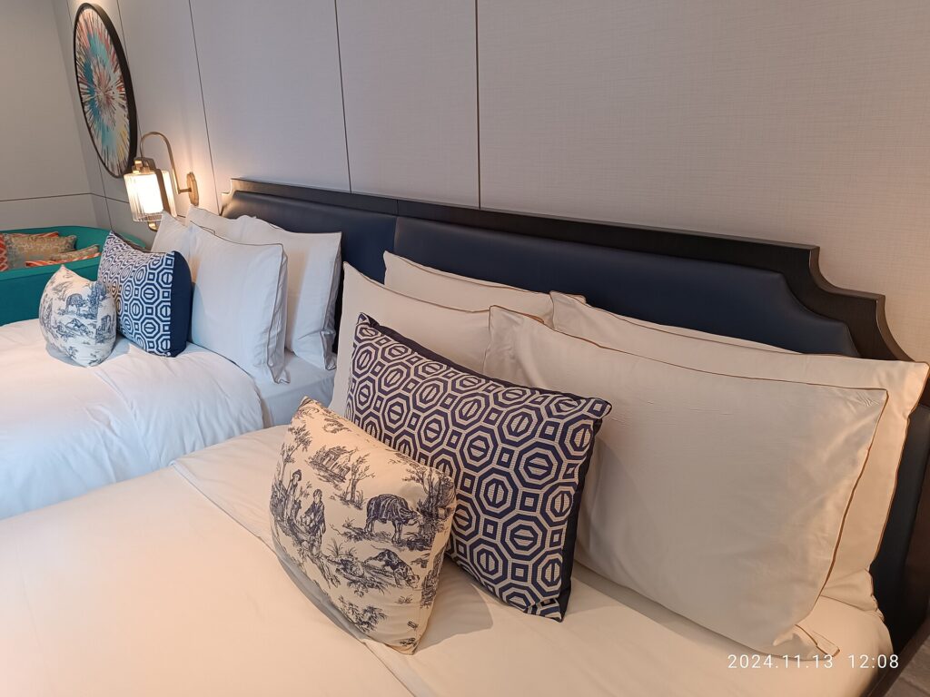 Hotel room with two made beds and a window overlooking a town street
