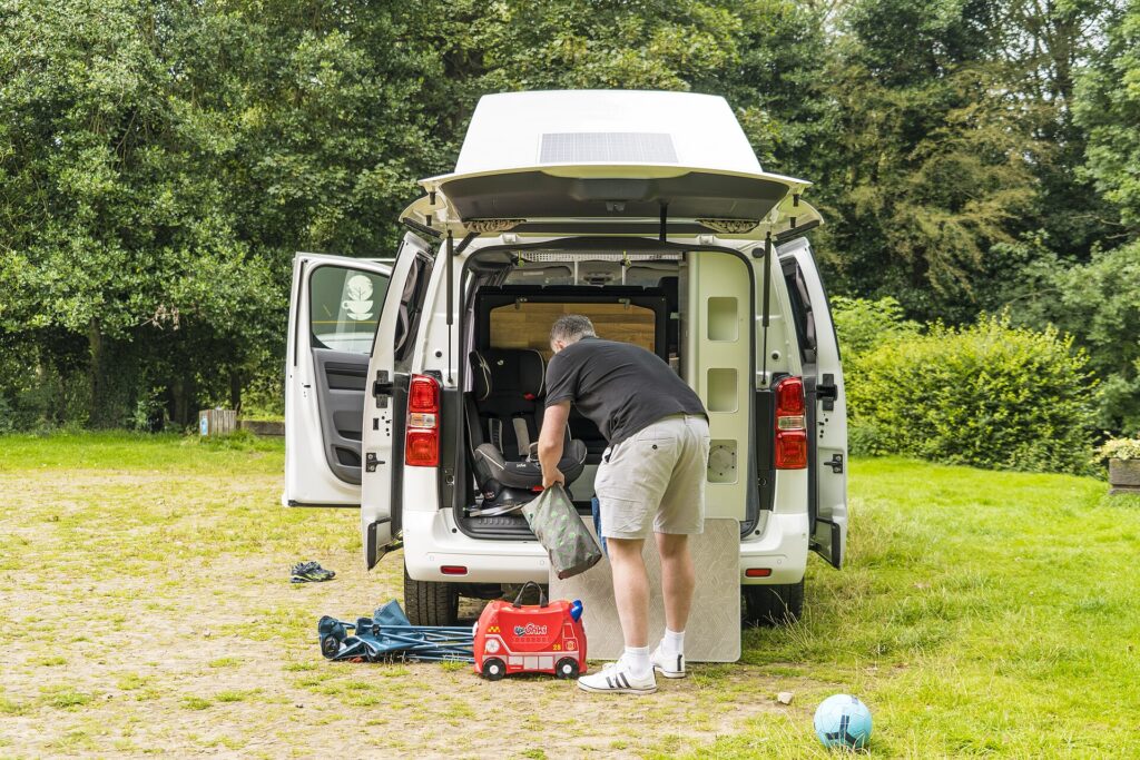 Festival camping gear sorted into labelled crates beside a car boot