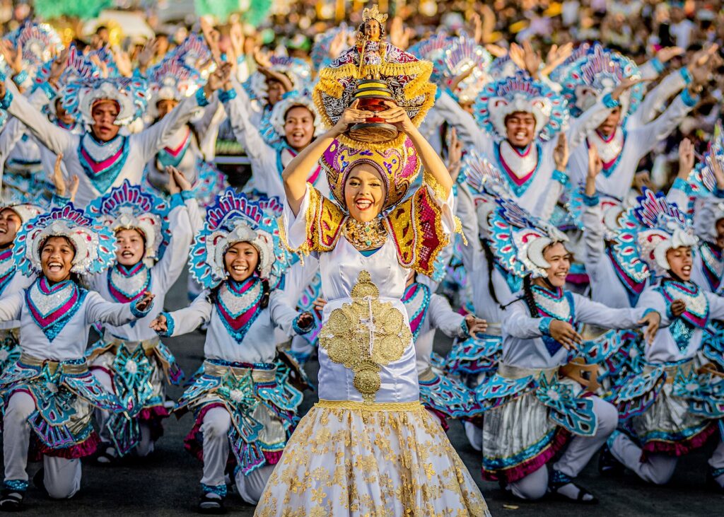 Street dancers in feathered costumes performing the Sinulog step during the Grand Parade in Cebu City