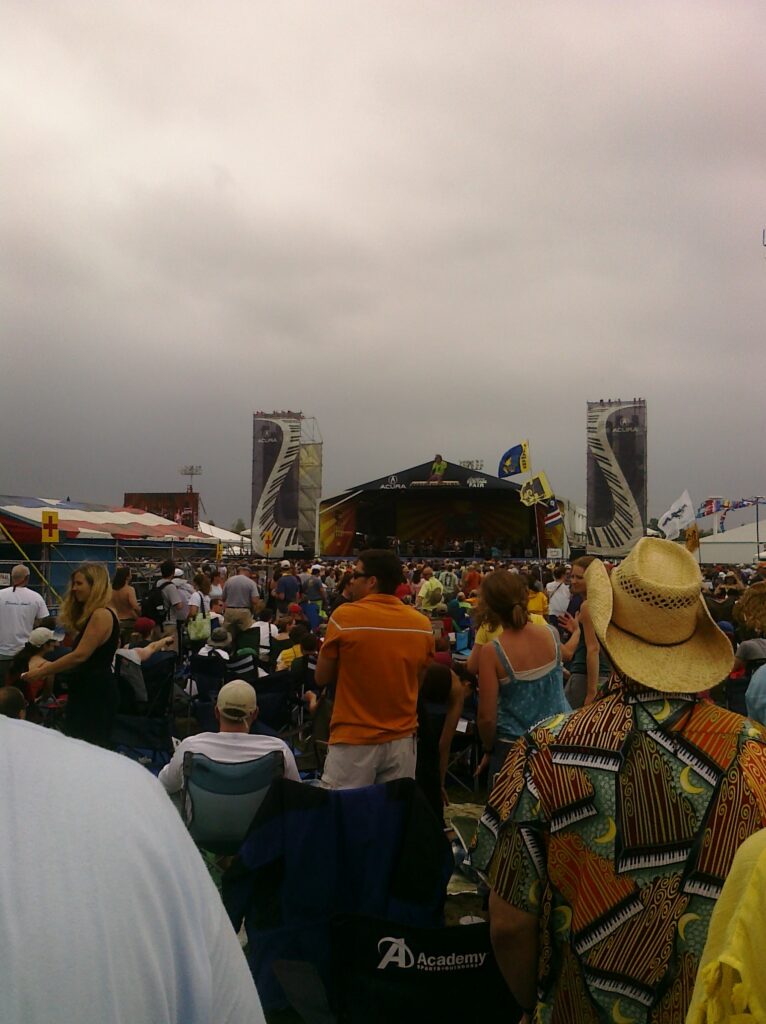 Festival crowd in wet weather wearing rain ponchos and holding umbrellas